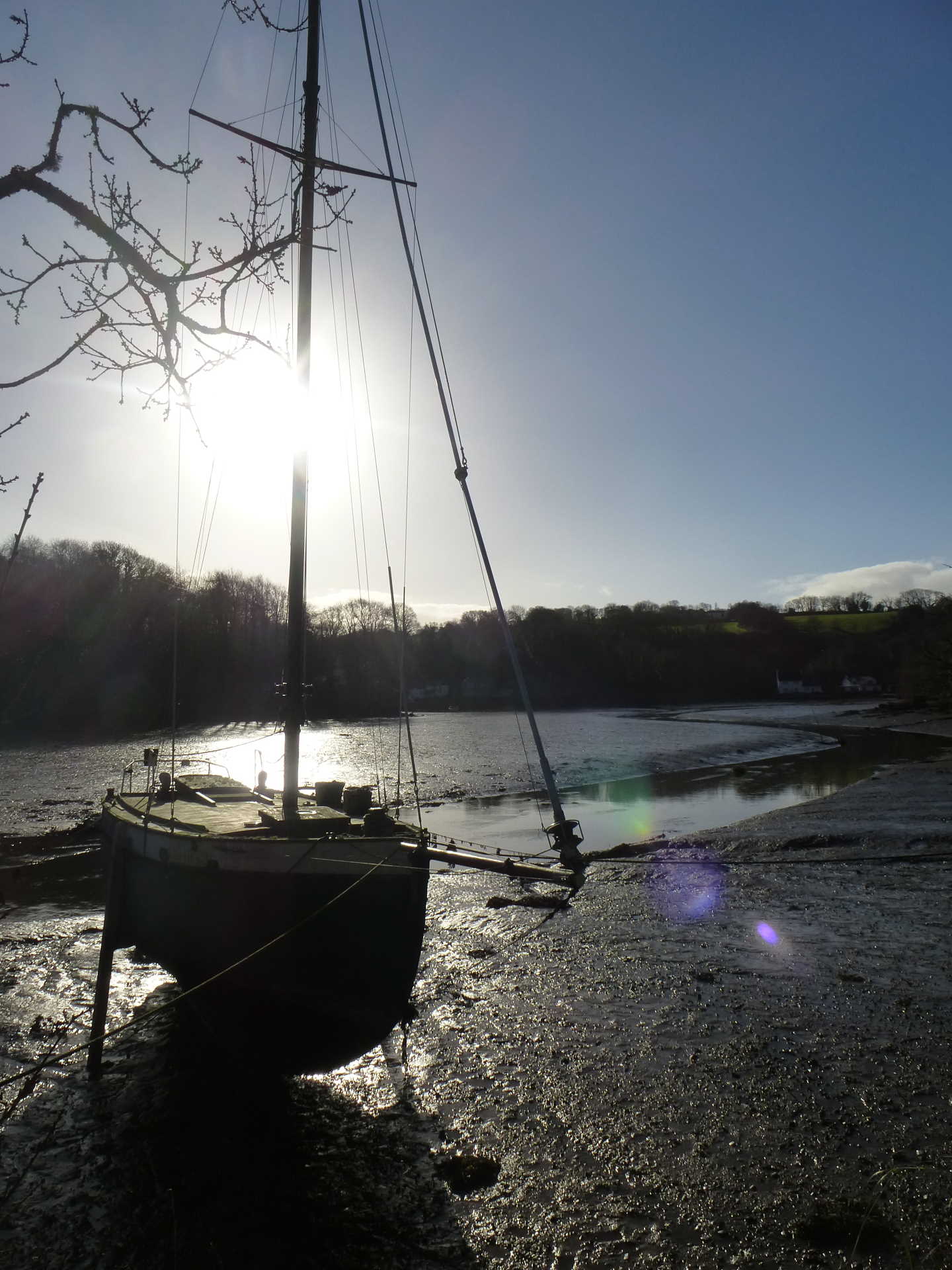 A boat out of the water in low tide sitting on a mud bank