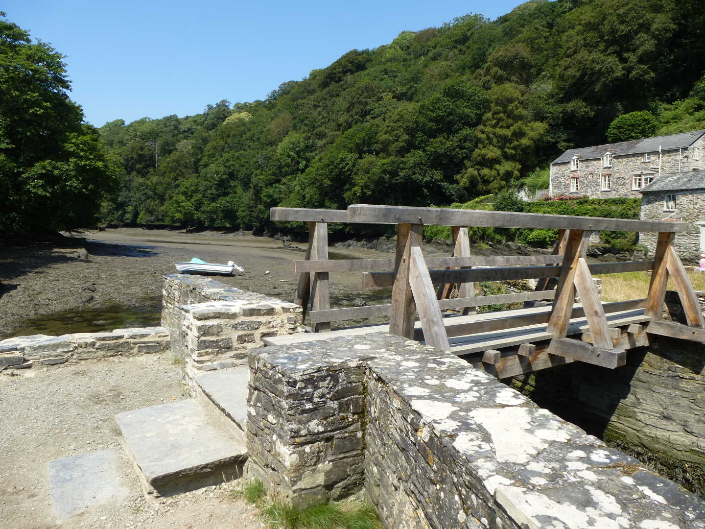 A small wooden bridge over the river with a boat in the background